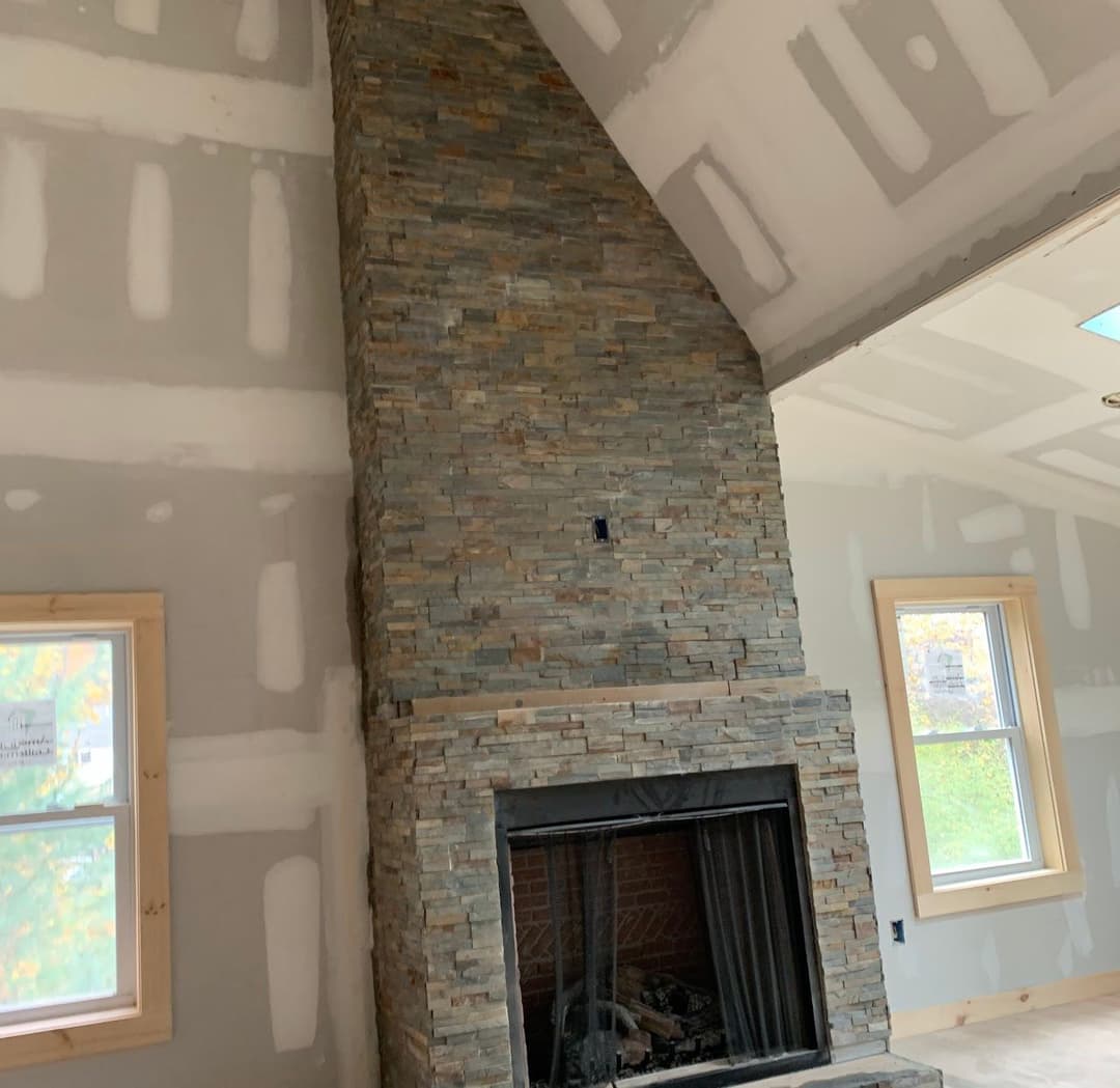 Stylish stone fireplace in a modern home under construction with drywall finishing.