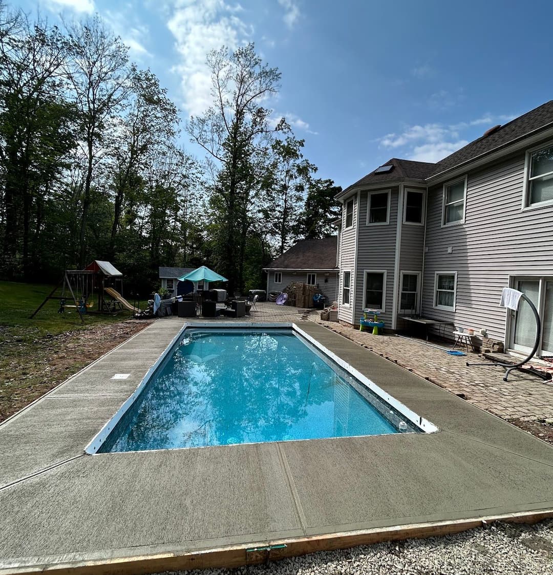 backyard swimming pool with patio furniture and play equipment under a clear sky