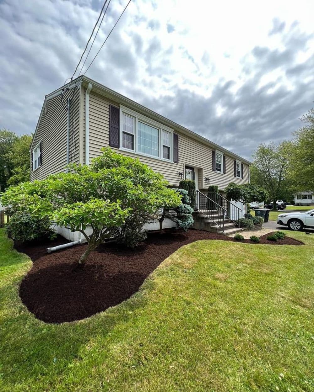 Front view of a well-landscaped house with fresh mulch and lush green shrubs.