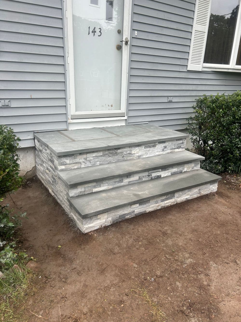 New stone steps leading to a front door, enhancing home entrance with modern design.